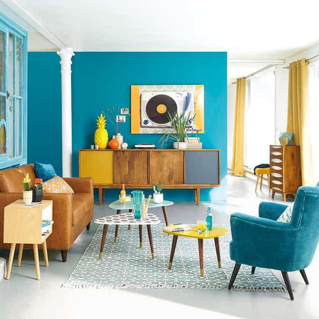 Olive green sofa in a modern living room with dark wooden flooring and vintage decor accents
