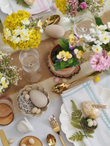 A festive Easter table decorated with pastel linens, floral centerpieces, and colourful eggs, creating a warm and inviting holiday atmosphere.