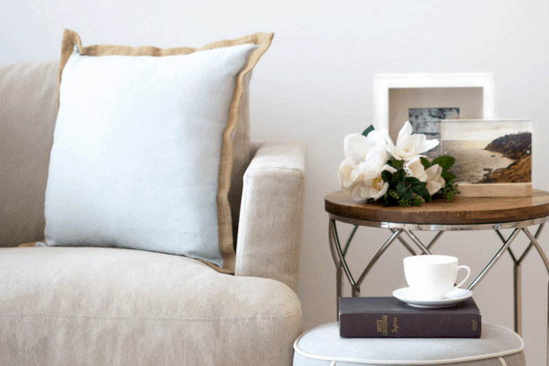 A stylish living room featuring a white sofa adorned with white flowers in a vase, creating a clean and serene ambiance for a home decor with flowers